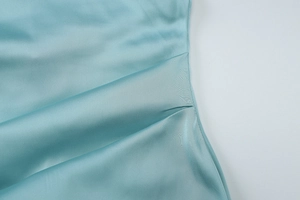 Makroaufnahme von hellblauem Satin-Abendkleid mit eleganten Drapierungen und glatter Textur