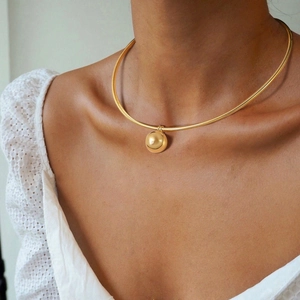 Close-up of a gold choker necklace with a large spherical pendant on a female model