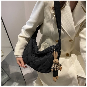 Black quilted hobo bag with cute rabbit pendant shown on model shoulder side view