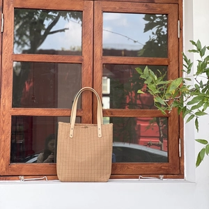 Detailed view of a vintage plaid cotton tote bag on a rustic window frame with plants