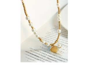 Macro shot of gold heart pendant and white pearls on an open book background