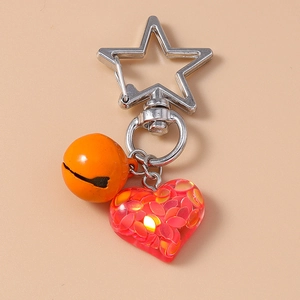 Detail of silver star clasp with orange bell and red glitter heart keychain pendant