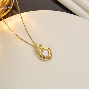 Gold heart castle necklace with white opal stone and crown detail on beige platform