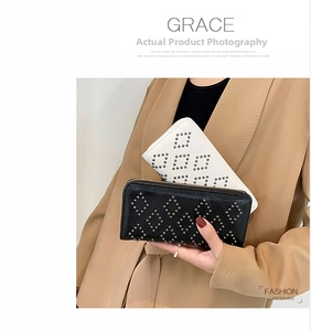 Nahaufnahme von zwei langen Clutch-Geldbörsen mit Nietenmuster in Schwarz und Weiß in der Hand