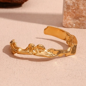 Close-up of 18K gold-plated stainless steel cuff with irregular lava texture