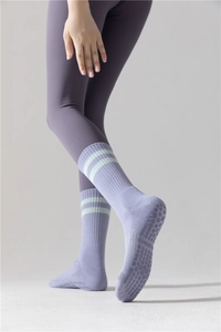 Détail de chaussettes de yoga mauves avec grips antidérapants et design à rayures mi-mollet