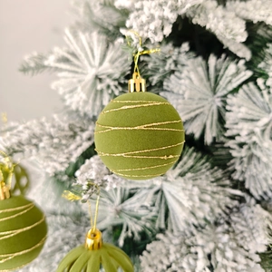 Gros plan d'une boule de Noël en velours vert avec motifs pailletés dorés et attache