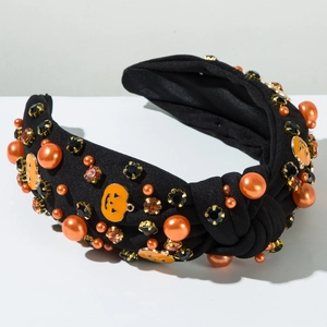 Detail eines verknoteten Halloween-Haarreifens mit orangefarbenen Perlen und Kürbis-Deko