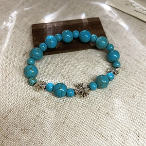 Détail macro du bracelet en perles de turquoise avec pendentifs croix sur tissu de jute