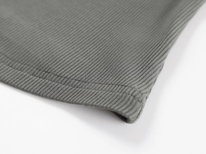 Macro detail of sage green ribbed knit fabric showing fine stitching and soft texture