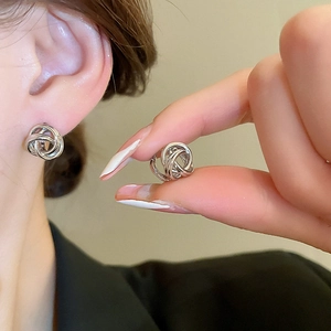 Close-up of silver minimalist twisted knot stud earrings worn by a model for a chic look
