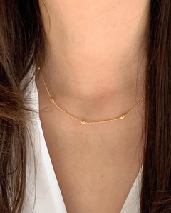 Nahaufnahme einer minimalistischen Goldperlenkette, elegant geschichtet am Hals