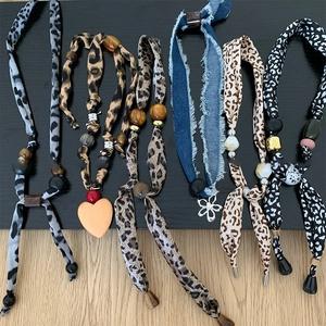 Detail view of retro fabric necklaces with leopard print and wooden heart pendants