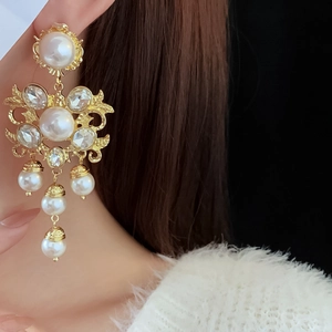 Close-up of vintage floral drop earrings with pearls and crystals on a model