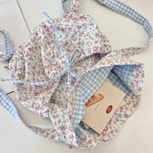 Floral canvas drawstring bag with blue gingham lining and adjustable strap detail