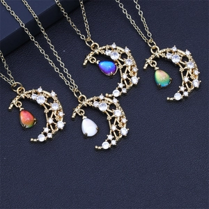 Detail of four moon and star necklaces with colorful teardrop gemstones on a dark surface