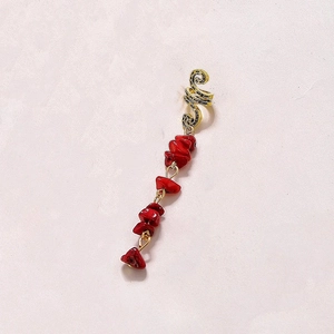 Detail of golden snake hair ring with red natural stone pendants on pink background