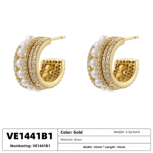 Detailed view of gold-plated brass C-shaped earrings with white pearls and pavé zircons