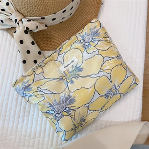 Close-up of elegant yellow floral jacquard makeup bag on soft quilted fabric