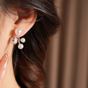 Macro view of luxury pearl stud earrings with silver fireworks floral cluster design