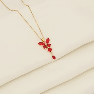 Detail of a gold butterfly pendant with red crystals on a delicate stainless steel chain