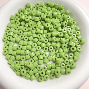 Vista macro di perline cilindriche in acrilico verde da 6mm per gioielli fatti a mano