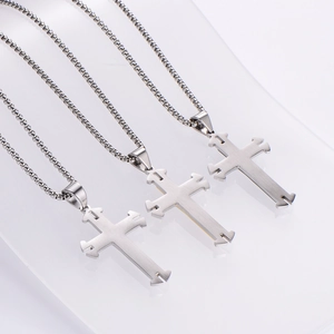 Three silver stainless steel layered cross necklaces with box chains on white background