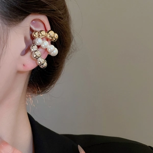 Dettaglio di tre ear cuff a forma di C con perle dorate, argente argento e bianche