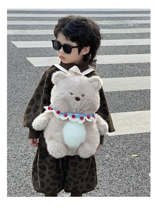 Detail of cute beige plush bear backpack worn by a toddler on a street background