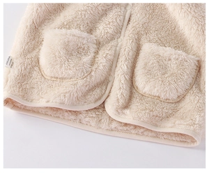 Dettaglio gilet in peluche color crema con trama soffice e bottoni a pressione tondi