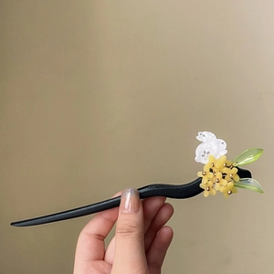 Détail d'un pic à cheveux avec fleurs jaunes, feuilles vertes et un pendentif lapin blanc