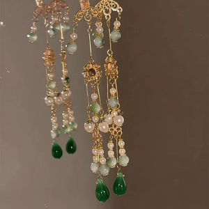 Gros plan de boucles d'oreilles chinoises à pompons avec perles vertes et dorées