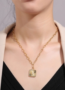 Close-up of a gold-plated sunflower pendant necklace featuring a white opal center on a model