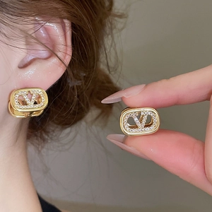 Close-up of 18k gold plated oval V-logo earrings with shimmering pavé zircon details