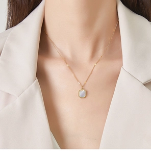 Close-up of a square white mother-of-pearl pendant on a gold chain necklace for women