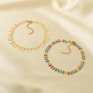 Detail of gold-plated fishtail anklets with colorful enamel leaf and pink disc charms