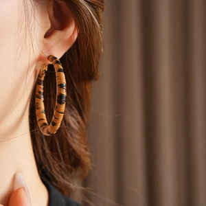 Gros plan d'une grande créole en cuir à motif léopard portée sur l'oreille