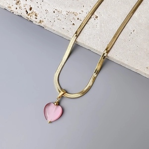 Close-up of 18K gold snake chain necklace featuring a pink heart-shaped cat eye stone pendant