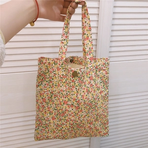 Vue détaillée du mini sac cabas en toile fleurie avec bouton pression en cuivre