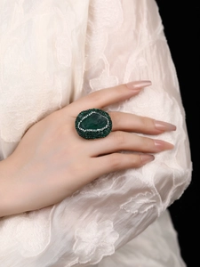 Close-up of oversized green oval stone ring with sparkling pavé rhinestones on finger