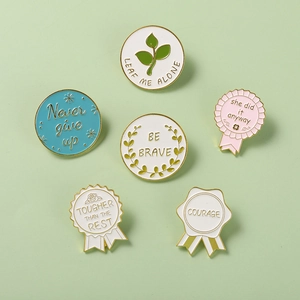 Detailed view of six inspirational enamel pins with letter patterns on a mint background