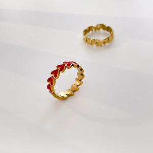 Macro detail of golden band ring with red heart enamel patterns and polished finish