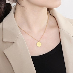 Collier en acier doré avec pendentif floral gravé, porté par un mannequin professionnel