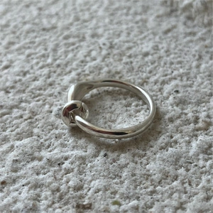 Minimalist 925 sterling silver knot ring with polished metallic finish on stone surface