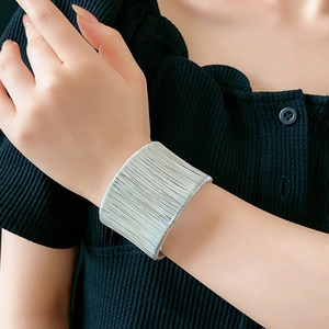 Dettaglio macro del bracciale rigido a strati in argento sul polso della modella