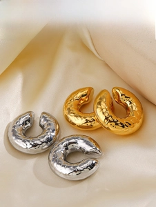 Detailed view of 18K gold and silver textured hollow C-hoop earrings on silk fabric