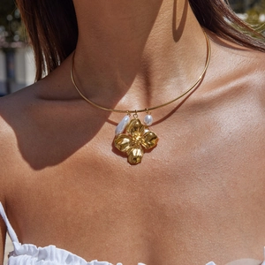 Detail of 18K gold stainless steel flower necklace with pearls on a model neck