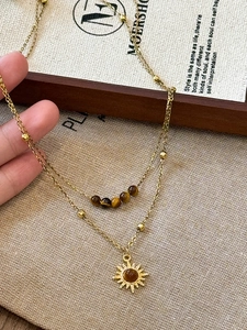 Close-up of a double-layer gold sun necklace with tiger eye beads and sun pendant