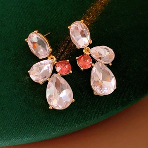 Macro shot of vintage gold drop earrings with pink faceted crystals on green velvet