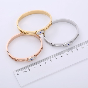 Polished evil eye bangles with gear-shaped cutout in gold, rose gold, and silver finishes